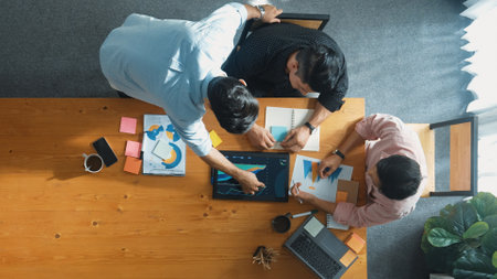 Executive manager explain financial graph to colleague at meeting room. Top aerial view of diverse marketing team sharing idea and planning strategy while sitting at table with tablet. Convocation.の写真素材