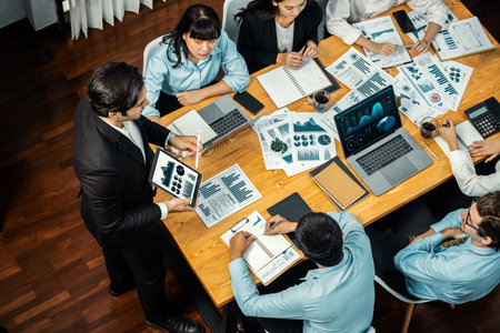 Wide top view of diverse group of business analyst team analyzing financial data report paper on meeting table. Chart and graph dashboard by business intelligence analysis. Meticulousの写真素材