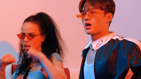 Close up of asian man and hispanic woman dancing together at party with led or neon light....