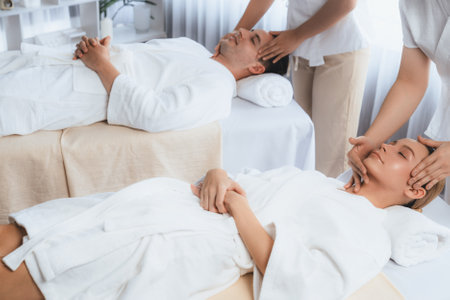 Caucasian couple enjoying relaxing anti-stress head massage and pampering facial beauty skin recreation leisure in dayspa modern light ambient at luxury resort or hotel spa salon. Quiescentの写真素材