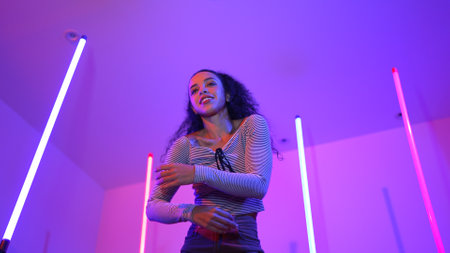 Low angle camera of hispanic dancer looking at camera and dancing to city pop music. Professional...