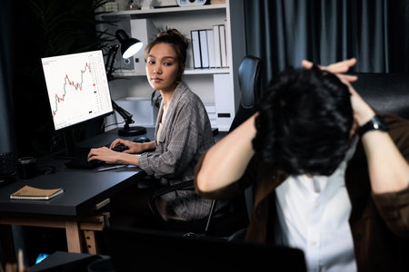 Businessman with stressful face working on laptop waiting email while coworker discussing together...