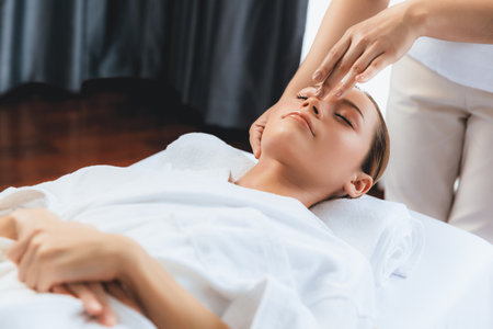 Caucasian woman enjoying relaxing anti-stress head massage and pampering facial beauty skin recreation leisure in dayspa modern light ambient at luxury resort or hotel spa salon. Quiescentの写真素材