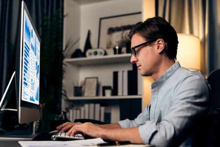 Smart businessman analyzing business paragraph dynamic database marketing analysis plan surrounded paper sheet and pc monitor report to compare with document data at home office at night.の写真素材