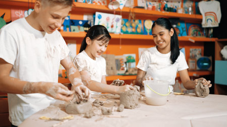 Caucasian highschool girl modeling cup of clay while looking smart boy in art class at workshop. Multicultural student playing or making cup of clay art in creative activity. Education. Edification.の写真素材