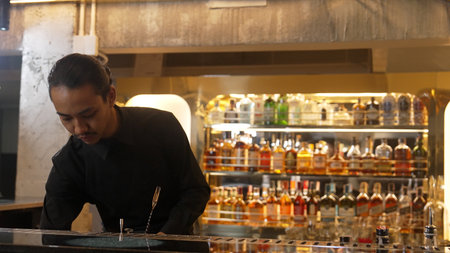 Asian bartender pouring mixed cocktail juice liqueur all ingredient into sliver shaker alcohol...