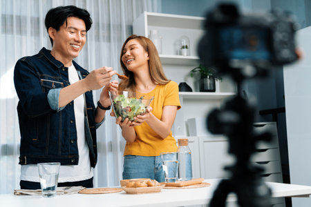 Cooking show live streaming with two chef influencers making mixed salad, all ingredients with dressing with good taste for easy special menu served with bun bread on table record by camera.の写真素材