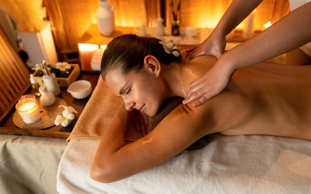Caucasian woman customer enjoying relaxing anti-stress spa massage and pampering with beauty skin recreation leisure in warm candle lighting ambient salon spa at luxury resort or hotel. Quiescentの写真素材