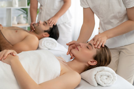 Caucasian couple enjoying relaxing anti-stress head massage and pampering facial beauty skin recreation leisure in dayspa modern light ambient at luxury resort or hotel spa salon. Quiescentの写真素材