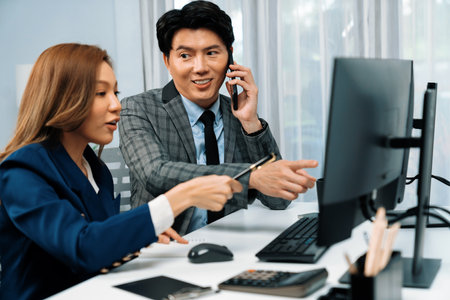Businessman calling with business partner on mobile phone while calculating stock exchange value with woman coworker on computer, analyzing company value sell or buy on up to date.の写真素材