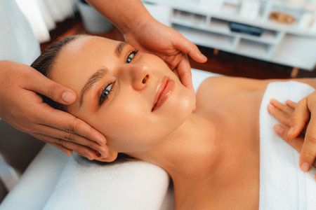 Caucasian woman enjoying relaxing anti-stress head massage and pampering facial beauty skin recreation leisure in dayspa modern light ambient at luxury resort or hotel spa salon. Quiescentの写真素材