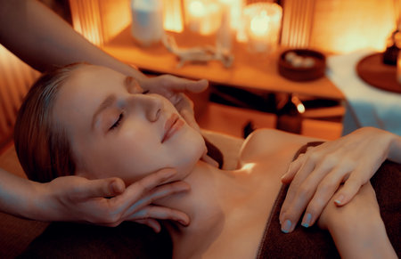 Caucasian woman enjoying relaxing anti-stress head massage and pampering facial beauty skin recreation leisure in warm candle lighting ambient salon spa in luxury resort or hotel. Quiescentの写真素材