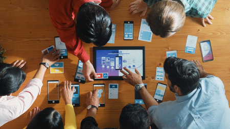 Top view of software developer team looking Ux Ui design for mobile phone interface from tablet...