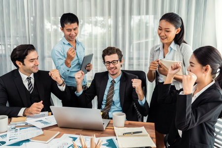 Group of happy businesspeople in celebratory gesture and successful efficient teamwork. Diverse race office worker celebrate after made progress on marketing planning in corporate office. Meticulousの写真素材