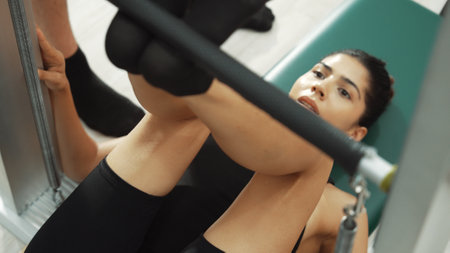 Pilates instructor guiding client foot placement during a reformer exercise for improving leg strength, and core stability. Close up of healthy girl feet making lower and lift pose. Habituate.の写真素材