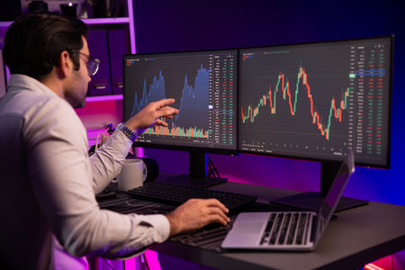 Smart trader businessman concentrating on dynamic stock exchange investment on pc and laptop showing...