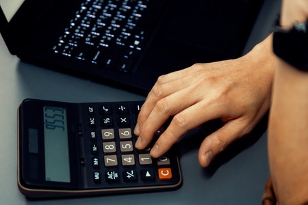 Cropped hand businessman calculating financial and accounting annual report showing digit gross profit or loss per total sales revenue of company this year with fixed or uncontrollable cost.の写真素材