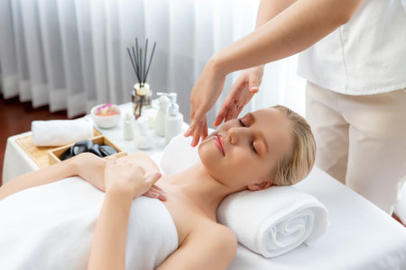 Caucasian woman enjoying relaxing anti-stress head massage and pampering facial beauty skin recreation leisure in dayspa modern light ambient at luxury resort or hotel spa salon. Quiescentの写真素材