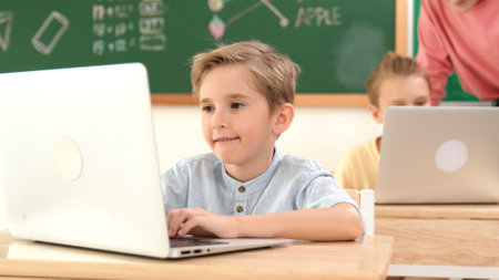 Caucasian boy working at laptop while diverse children programing software system. Teacher and...