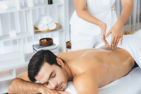 Caucasian man customer enjoying relaxing anti-stress spa massage and pampering with beauty skin recreation leisure in day light ambient salon spa at luxury resort or hotel. Quiescentの写真素材