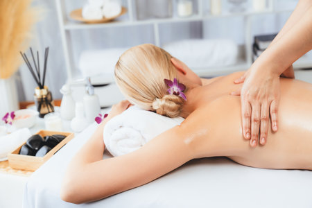 Caucasian woman customer enjoying relaxing anti-stress spa massage and pampering with beauty skin recreation leisure in day light ambient salon spa at luxury resort or hotel. Quiescentの写真素材
