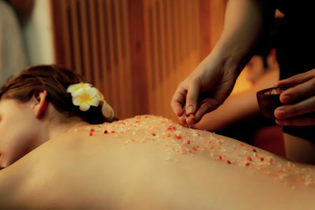 Closeup couple customer having exfoliation treatment in luxury spa salon with warmth candle light ambient. Salt scrub beauty treatment in Health spa body scrub. Quiescentの写真素材