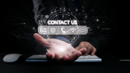 A hand extends towards a glowing contact us icon surrounded by digital communication symbols, representing connection and support in business and technology settings.の写真素材
