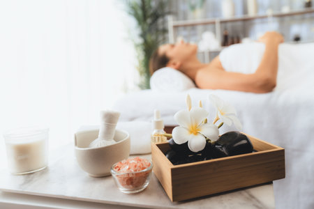 Aromatherapy massage on daylight ambiance or spa salon composition setup with focus decor and spa accessories on blur woman enjoying blissful aroma spa massage in resort or hotel background. Quiescentの写真素材