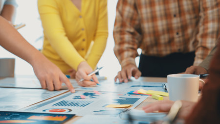 A team of professionals collaboratively analyzing data reports displayed on a table, focusing on...