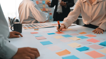 A vibrant office scene captures a diverse team engaged in a brainstorming session, utilizing sticky notes for creative planning and brainstorming innovative solutions together.の写真素材