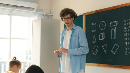 Skilled teacher walking at classroom while looking at student homework. Professional instructor...