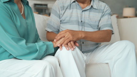 Close up of stressed senior man thinking about working problem while wife holding hand to comfort...
