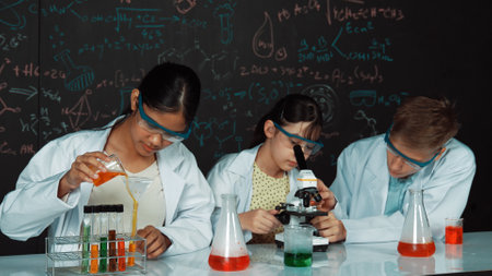 Teenager drop sample in microscope while girl inspect carefully at blackboard with chemistry theory. Scientist pour chemical product in tube and prepare for experiment.の写真素材