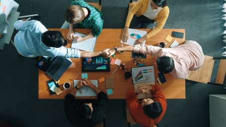 Top view of business team clapping hand and shaking hands together for celebrate successful deal. Top down aerial view of business man present start up project at whiteboard.の写真素材