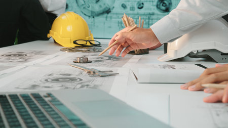 Engineers work together on technical drawings and designs, showcasing teamwork and innovation in a...