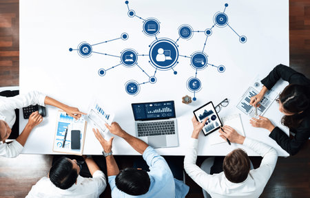 A dynamic business meeting showcases professionals analyzing data using various digital devices...