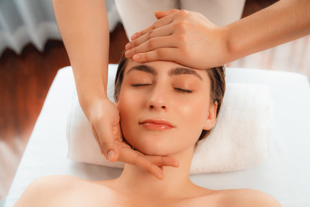 Caucasian woman enjoying relaxing anti-stress head massage and pampering facial beauty skin recreation leisure in dayspa modern light ambient at luxury resort or hotel spa salon. Quiescentの写真素材
