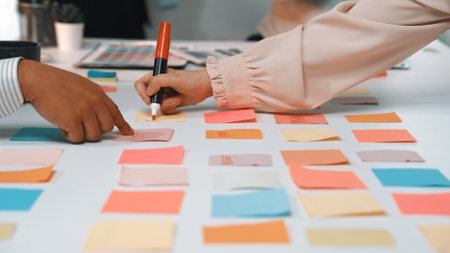 Two hands engage with colorful sticky notes on a table, showcasing a vibrant brainstorming session in a collaborative workspace to generate innovative ideas and strategies.の写真素材