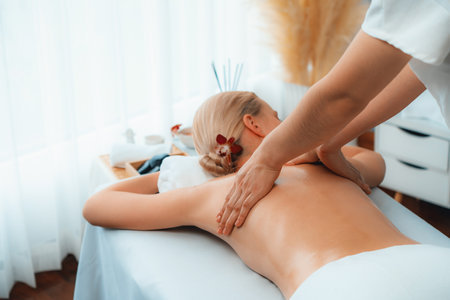 Caucasian woman customer enjoying relaxing anti-stress spa massage and pampering with beauty skin recreation leisure in day light ambient salon spa at luxury resort or hotel. Quiescentの写真素材