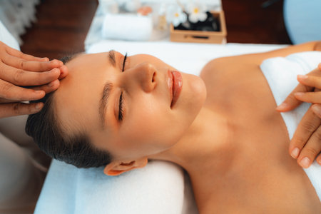 Caucasian woman enjoying relaxing anti-stress head massage and pampering facial beauty skin recreation leisure in dayspa modern light ambient at luxury resort or hotel spa salon. Quiescentの写真素材
