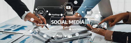 Team Collaboration on Social Media Strategy with Hands Working on Documents and Digital Interfaces Displaying Social Platforms and Data Insights.の写真素材