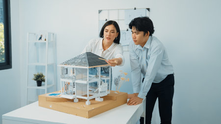 Closeup of young professional skilled architect engineer team focusing on checking the house model structure at modern office. Creative professional design and teamwork concept. Immaculate.の写真素材
