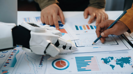 A human and a robot collaborate in a business meeting, analyzing various charts and graphs. This image represents the future of teamwork and innovation in decision-making.の写真素材