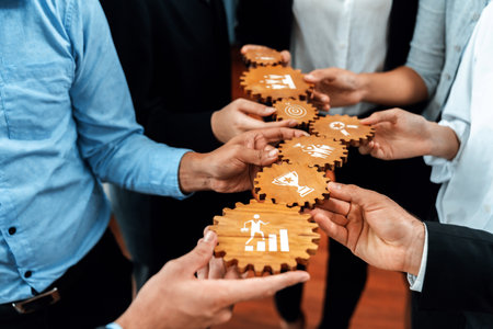 This image depicts a team of professionals collaborating with wooden gears featuring icons that symbolize business strategies and success, highlighting teamwork and innovation.の写真素材