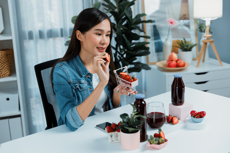 Smiling young beautiful Asian reviewing tasty mixed strawberry and cherry juice detox drinks, showing healthy product to promote for special promotion selling on social media online record.の写真素材