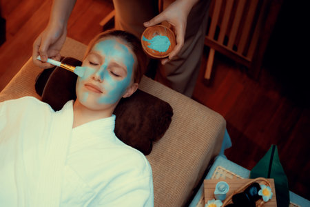 Serene ambiance of spa salon, woman customer indulges in rejuvenating with luxurious face cream massage with warm lighting candle. Facial skin treatment and beauty care concept. Quiescentの写真素材