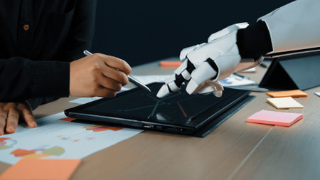 A human and a robot engage in a collaborative design process, using a touchscreen tablet to merge technology with creativity in a modern workspace.の写真素材