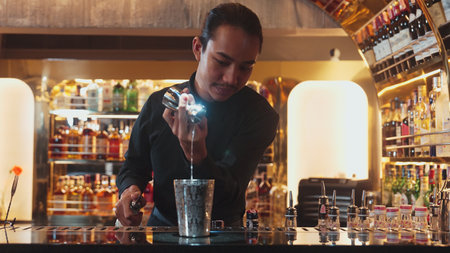 Asian bartender pouring mixed cocktail juice liqueur all ingredient into sliver shaker alcohol...