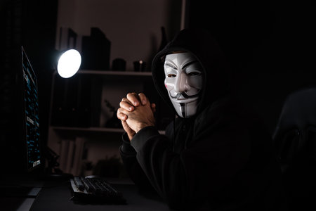 White smiling anonymous mask looking camera with hands joining, installing virus encryption by hack program, data server system in privacy on computer ransom. Surmise.の写真素材