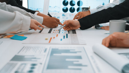 Participants engage in a collaborative business meeting, analyzing detailed charts and graphs on the...